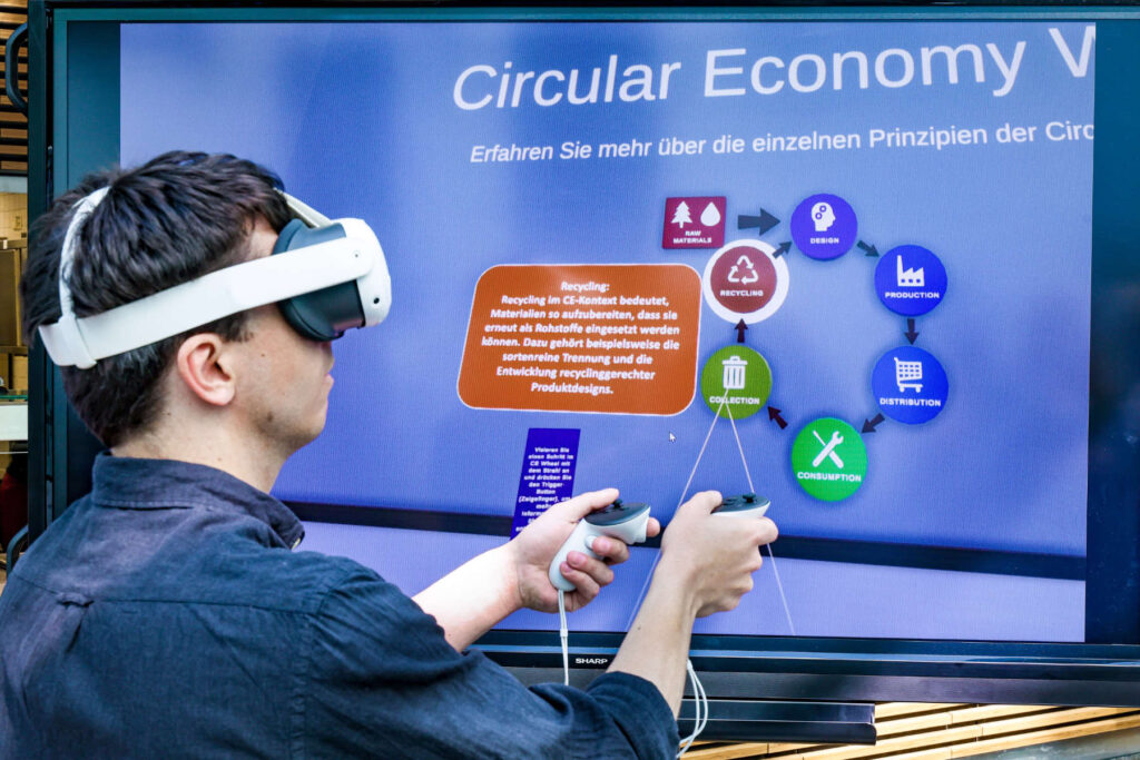 Person interagiert mittels VR-Brille mit einer Infostation zu den Prinzipien der Circular Economy im Gesamtdemonstrator des Transferhub Digitalisierung und Circular Economy.